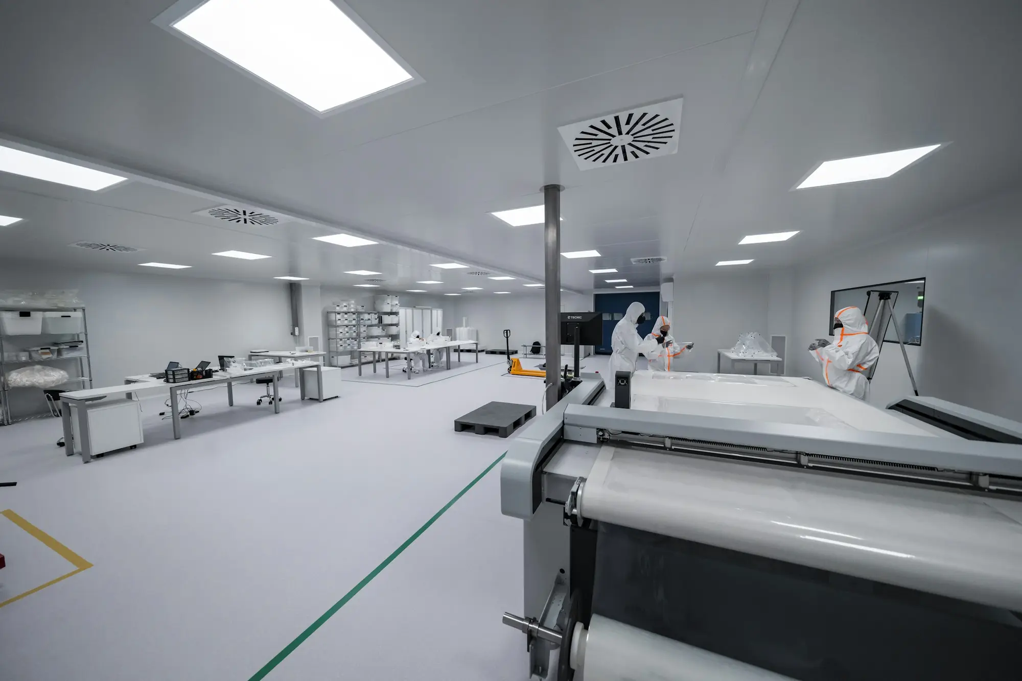 Technicians in full clean room gowns in a controlled manufacturing space